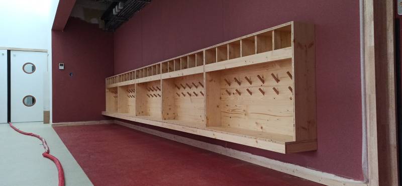 Ensemble de casiers suspendus avec bancs intégrés et patères bois, installé dans un couloir d’accueil. Finition naturelle et fonctionnelle, pensée pour les enfants.